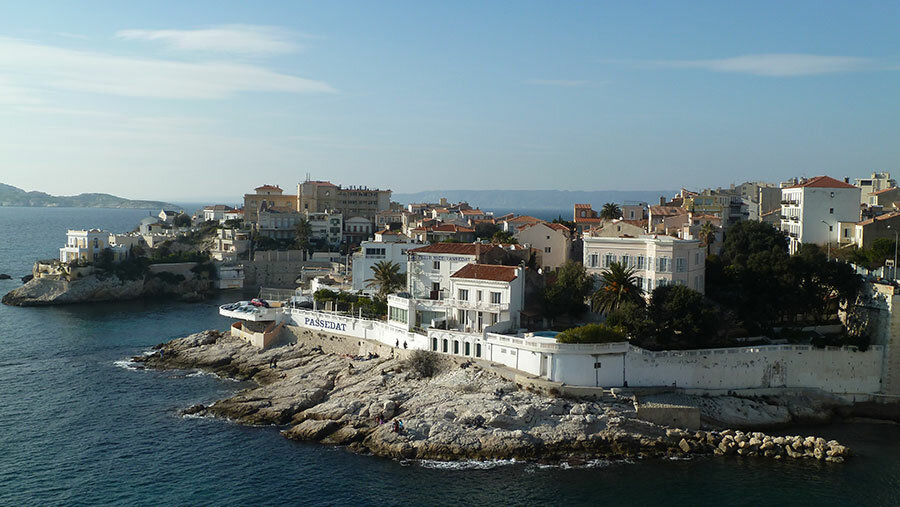 La corniche de Malmousque, entre les anses de Maldormé (côté ouest, à gauche de l'image) et de la Fausse Monnaie (côté est, à droite) vues du Parc Valmer, dans le quartier d'Endoume et le 7e arrondissement de Marseille. Au centre, la façade maritime du restaurant « Le Petit Nice Passedat ». À gauche sur la pointe, la villa de la Petite Ourse © TouN via Wikimedia Commons - Licence Creative Commons